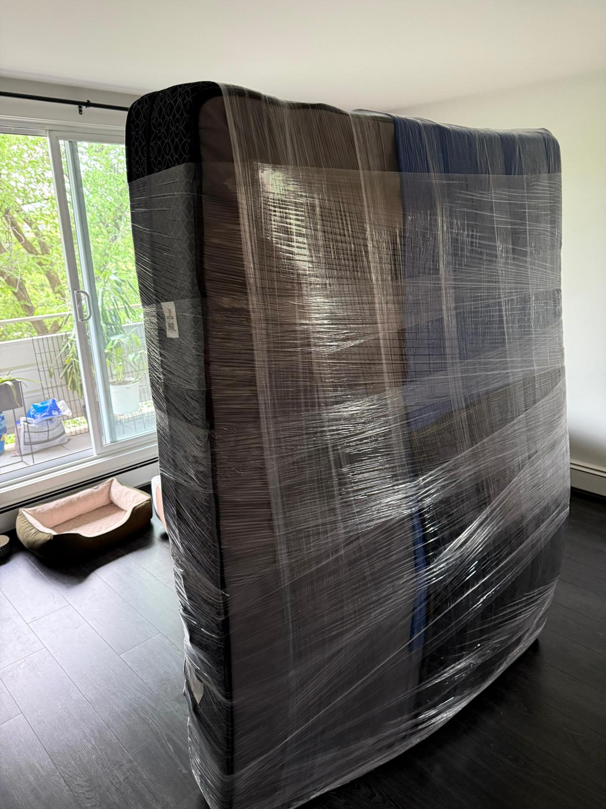Mover carefully carrying a wrapped bed frame and mirror